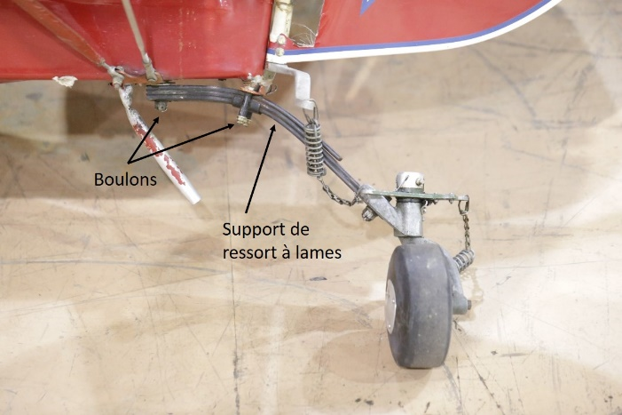 Assemblage de la roulette de queue, avec des flèches indiquant les boulons et le support de ressort à lames (Source : BST)